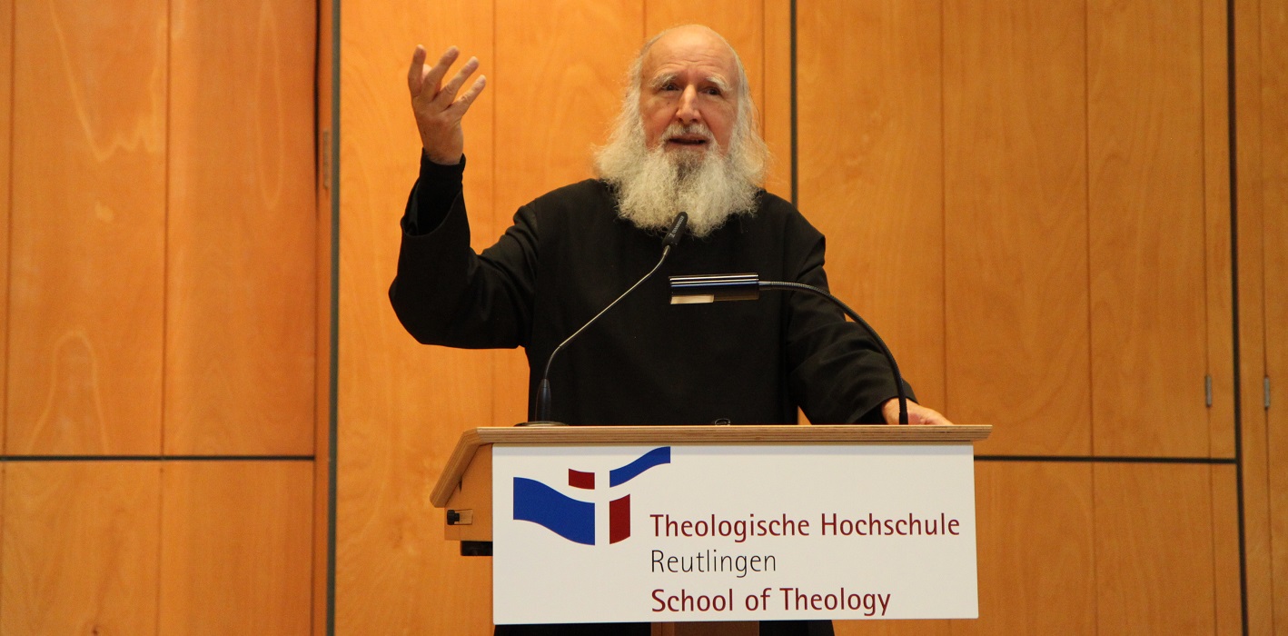 Wunderbar blühende rote Rosen rund um ein offenes Tor mit Blick in die Weite - das ist das Bildmotiv für den Studiengang Christliche Spiritualität.